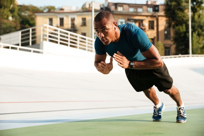 Image of a man in a vertical position in the air with his hands clasped together like he is doing a bodyweight exercise
